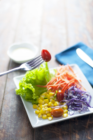 Fresh red tomato and vegetable salad on wooden table. Eating for healthy.の写真素材