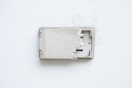 Electric plug cover was dog bite. Wall cover plug socket damage. Outdoor electric outlet on white wall.の写真素材
