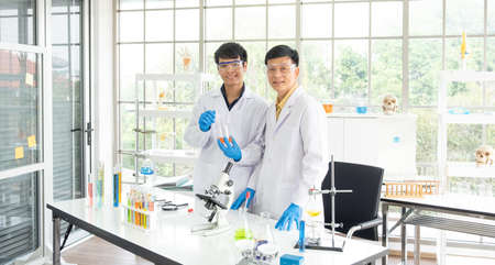 Science, Chemistry, Technology, Biology and Laboratory concept - Portrait of Asian senior and junior scientists is showing their experimental results in a test glass beaker.の写真素材