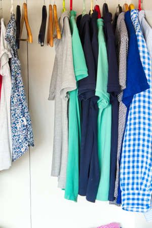 Group of garments hanging on hangers and displayed in a flea market as second-hand clothesの写真素材