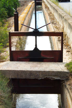 Irrigation canal with water to irrigate the fields of vegetables and fruit treesの写真素材