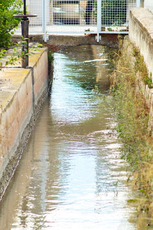 Irrigation canal with water to irrigate the fields of vegetables and fruit treesの写真素材