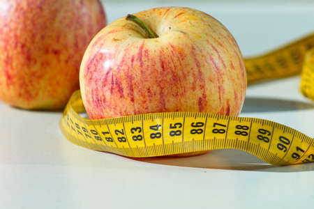 Set of two delicious and healthy apples with a measuring tape aroundの写真素材