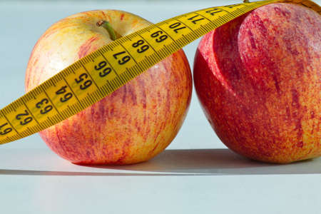 Set of two delicious and healthy apples with a measuring tape aroundの写真素材