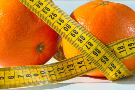 Set of two delicious and healthy oranges with a measuring tape aroundの写真素材