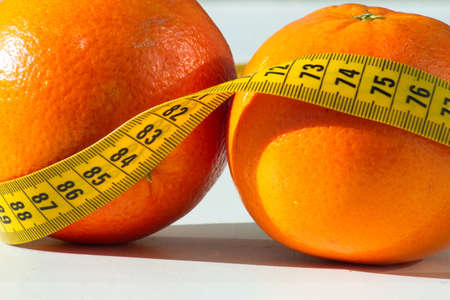 Set of two delicious and healthy oranges with a measuring tape aroundの写真素材