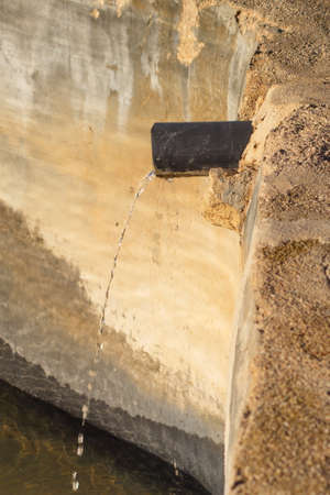 Small stream of water that falls into an irrigation pond in the middle of a droughtの写真素材