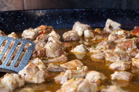Preparation of a tasty rice with ribs with broth and pieces of pork over a wood fireの写真素材