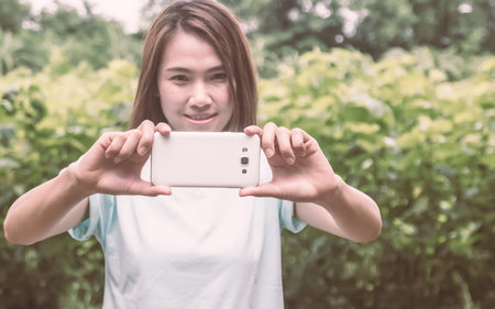 Smartphone focused. Pretty young woman taking picture with camera phone.の写真素材