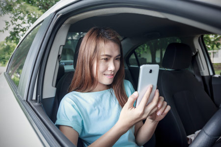 Woman using smart phone in her car. Soft focut.