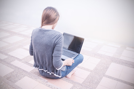 Young asian woman using laptop on steps outdoors. Soft focused.の写真素材