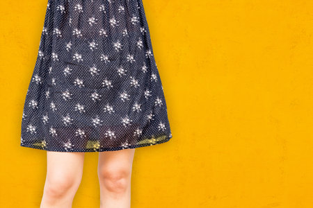 Women's legs in a skirt on a yellow background