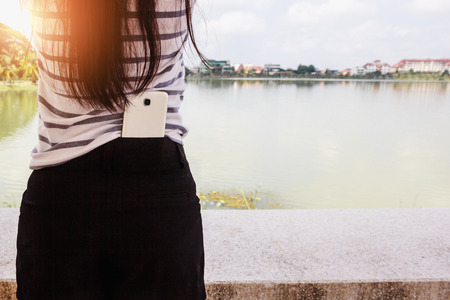 White smart mobile phone in back woman.の写真素材