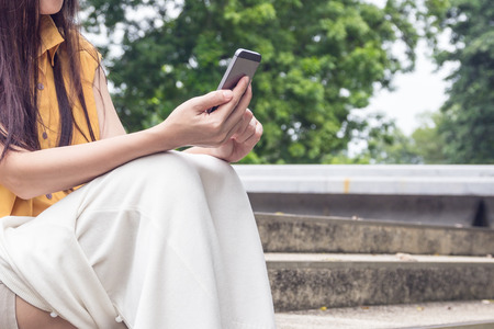 Young woman sitting on stairs with their smartphones, filter colored picture style.の写真素材