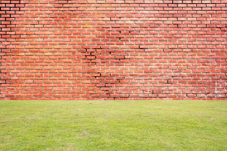 Old red brick wall background with green grassの写真素材
