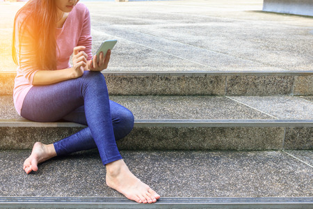 Young woman sitting on stairs with their smartphones.の写真素材