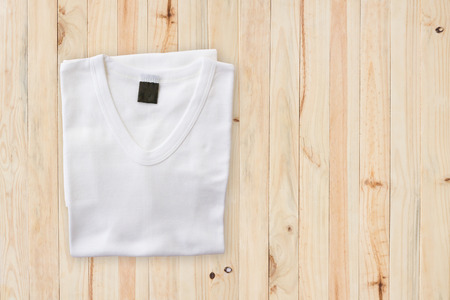 Top view of white T-Shirt on wood floor backgroundの写真素材
