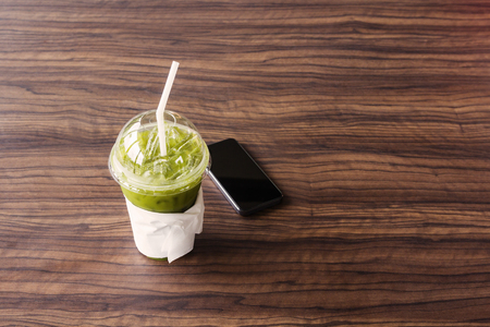 Ice green tea with smart phone on wood table.の写真素材