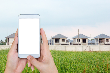 Hand holding and touch screen smart phone, looking for a new houses in suburb.の写真素材