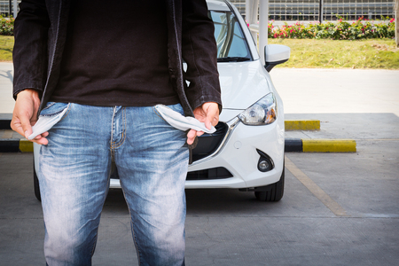 Man showing his empty pockets with white car on the car park.の写真素材