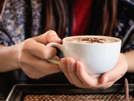Close up hand holding cup of hot coffee in the cafeの写真素材
