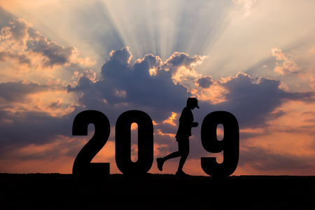 Silhouette woman running of Happy new year 2019 at sunset background.の写真素材