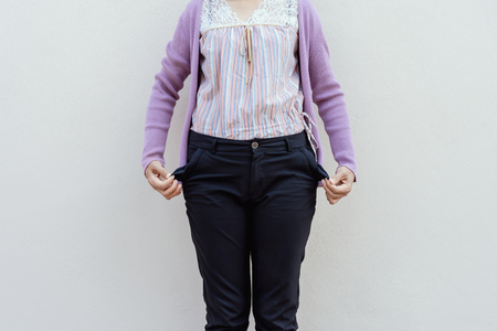 Woman showing her empty pocket on wall background.の写真素材