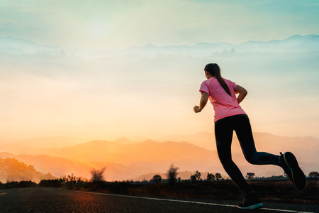 Young woman enjoys running outside with beautiful summer evening in the countryside.の写真素材