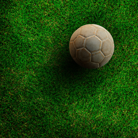 Old ball on green grass soccer field.の写真素材