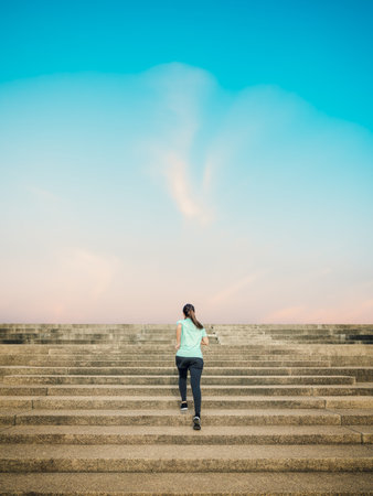 Beautiful woman running on the stairway with a view of the sky in the morning.