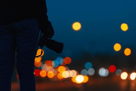 Young holding the camera with abstract blurred light in night time of urban with bokeh background.の写真素材