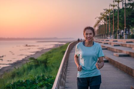 Woman running on street with a view of river in the morning.の写真素材