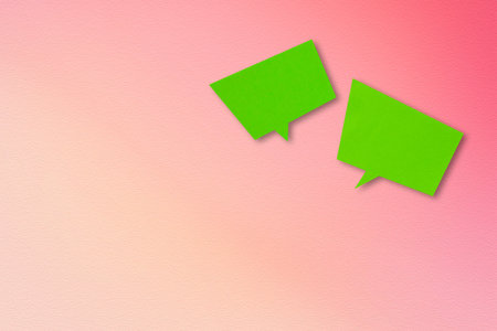 Green paper speech bubble on a pink background.