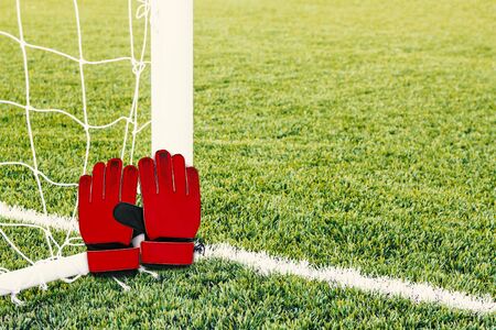 Red goalkeeper gloves with soccer goal background.の写真素材