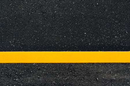 Asphalt road textured with yellow line for background.の写真素材