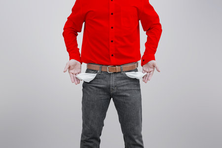 Man showing his empty pockets on gray wallの写真素材
