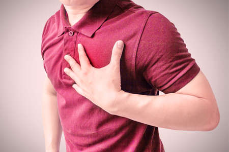 An adult man uses his hand to hold his chest. After having a heart attack symptom. Concepts of health care and medications for men.の写真素材