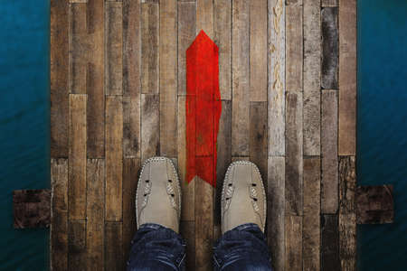 Top view of man standing near the red arrow on old bridge wood floor background.の写真素材