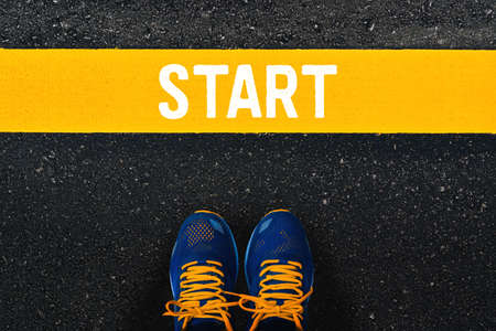 word Start on yellow line with blue sneaker or sport shoes on asphalt road background.の写真素材