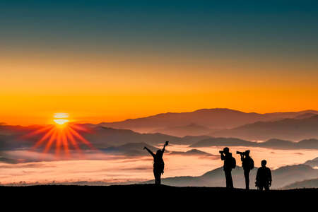 Silhouette image of a group traveler men and women taking photos with sunrise in the morning on mountains natural background.の写真素材
