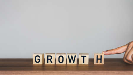 Man's hand scrolling the letter "h" to combine with the rest of the words to get the word "growth" on wooden cubes block. Business growth in concept.の写真素材
