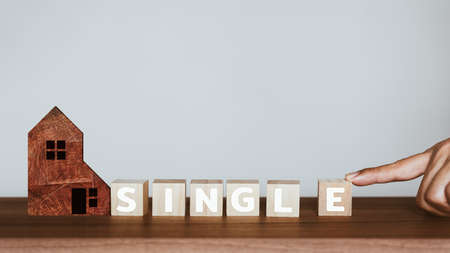 Man's hand scrolling the letter "e" to combine with the rest of the words to get the word "single" on wooden cubes block. Concept of being singleの写真素材