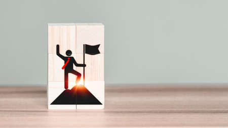 The leader or winner or businessman icon on wooden cube block with business success and goal achievement concept. Symbols for winners, successes and leaders.の写真素材