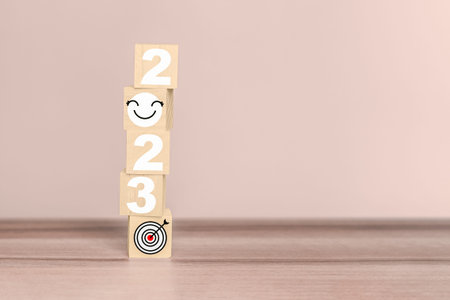 2023 number and smile face and goal icon on wooden cube block on wood table background. Next year...