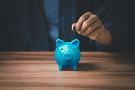 Man putting coin into piggy bank for saving money concept, business finance and investment.の写真素材
