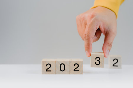 Hand holding a wooden cube with numbers 2023 on white background. Goal in the new year 2023. Business development strategy, advancement and goal conceptの写真素材