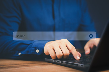 Businessman's hand working with computer laptop on desk in home. Searching Browsing Internet Data Information with blank search bar. Search Engine Optimization SEO Networking Concept.の写真素材