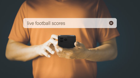 Football fan checking mobile phone gor live football scores in his home. Searching Browsing Internet Data Information with search bar. Search Engine technology networking Concept.の写真素材