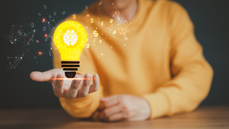 Man holding a glowing abstract light bulb on a wooden table, business problem solving ideas and creative marketing ideas Inventing and learning new things.の写真素材