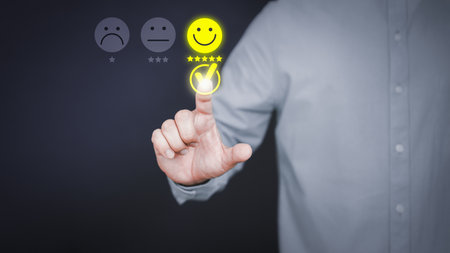 Man touching the virtual screen on the happy smiley face icon to give satisfaction in service. Rating very impressed. Customer service, testimonial and satisfaction concept.の写真素材
